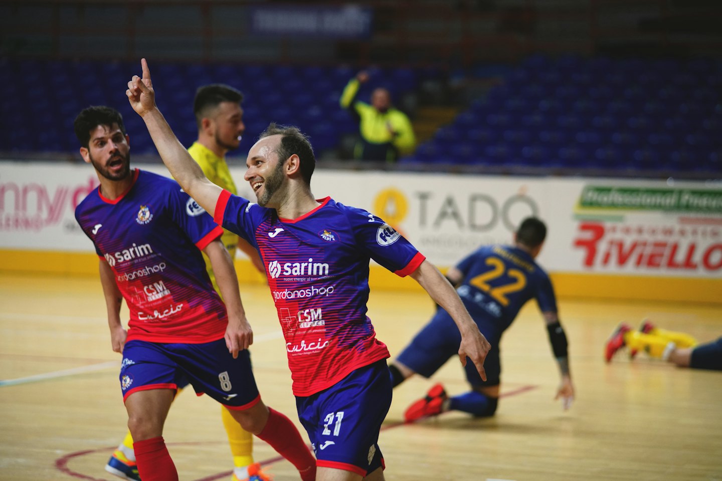 Due giocatori di futsal in divisa festeggiano una vittoria su un campo indoor.