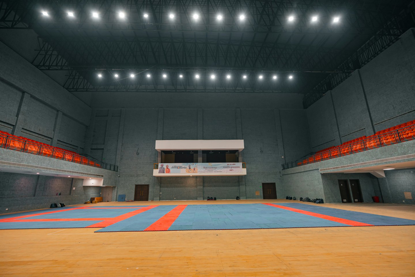 Pavimento vuoto di un'arena sportiva con tappeti colorati e posti a sedere su più livelli.